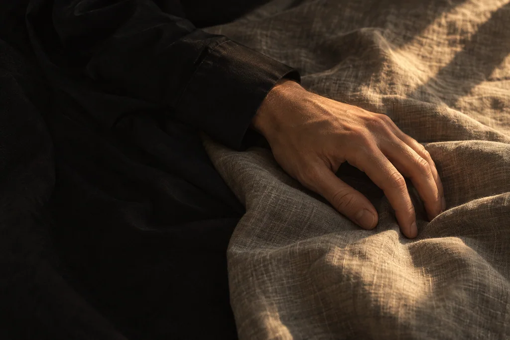 A hand resting on linen, lit by evening light